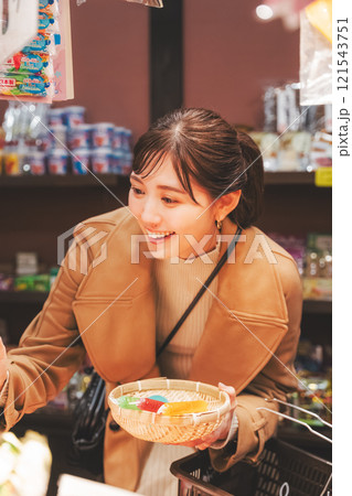 昔ながらの駄菓子屋で懐かしく買い物をする若い女性【撮影協力・お米・駄菓子屋 加賀田米穀店】 121543751