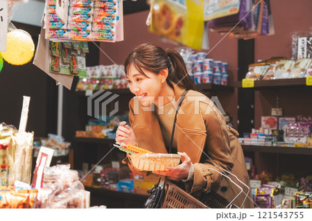 昔ながらの駄菓子屋で懐かしく買い物をする若い女性【撮影協力・お米・駄菓子屋 加賀田米穀店】 121543755