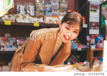 昔ながらの駄菓子屋で懐かしく買い物をする若い女性【撮影協力・お米・駄菓子屋 加賀田米穀店】 121543758