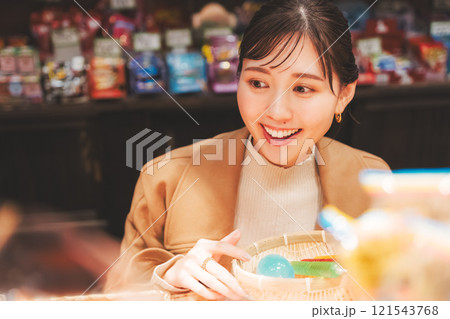 昔ながらの駄菓子屋で懐かしく買い物をする若い女性【撮影協力・お米・駄菓子屋 加賀田米穀店】 121543768