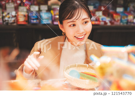 昔ながらの駄菓子屋で懐かしく買い物をする若い女性【撮影協力・お米・駄菓子屋 加賀田米穀店】 121543770