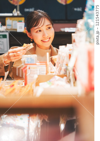 昔ながらの駄菓子屋で懐かしく買い物をする若い女性【撮影協力・お米・駄菓子屋 加賀田米穀店】 121543775