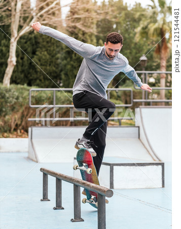 Skateboarder performing a trick on a rail at a skatepark. Skateboarder performing a trick on a rail at a skatepark. 121544481