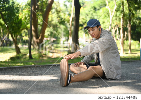 Young sporty man stretching outdoors before running in nature during sunny summer day Young sporty man stretching outdoors before running in nature during sunny summer day 121544488