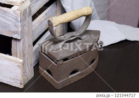 Old iron, heated by hot coals. Standing next to a wooden box. Old iron, heated by hot coals. Standing next to a wooden box. 121544717