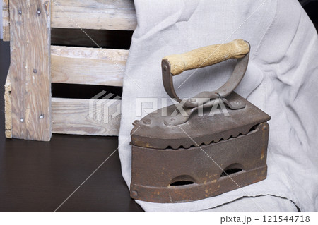Old iron, heated by hot coals. Standing next to a wooden box. Old iron, heated by hot coals. Standing next to a wooden box. 121544718