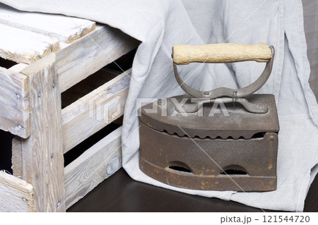 Old iron, heated by hot coals. Standing next to a wooden box. Old iron, heated by hot coals. Standing next to a wooden box. 121544720