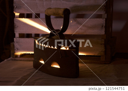 Old iron, heated by hot coals. In the twilight you can see the light of burning coals. Standing next to a wooden box. 121544751