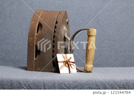 Old iron, heated by hot coals. Located on gray fabric. Nearby a greeting card. Old iron, heated by hot coals. Located on gray fabric. Nearby a greeting card. 121544764