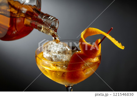 Old-fashioned cocktail garnished with orange peel. 121546830
