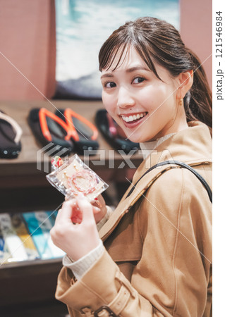 昔ながらの駄菓子屋で懐かしく買い物をする若い女性【撮影協力・お米・駄菓子屋 加賀田米穀店】 121546984
