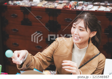 昔ながらの駄菓子屋で懐かしく買い物をする若い女性【撮影協力・お米・駄菓子屋 加賀田米穀店】 昔ながらの駄菓子屋で懐かしく買い物をする若い女性【撮影協力・お米・駄菓子屋 加賀田米穀店】 121546987