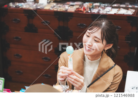 昔ながらの駄菓子屋で懐かしく買い物をする若い女性【撮影協力・お米・駄菓子屋 加賀田米穀店】 昔ながらの駄菓子屋で懐かしく買い物をする若い女性【撮影協力・お米・駄菓子屋 加賀田米穀店】 121546988