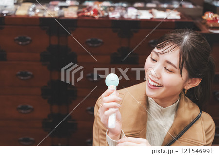 昔ながらの駄菓子屋で懐かしく買い物をする若い女性【撮影協力・お米・駄菓子屋 加賀田米穀店】 121546991