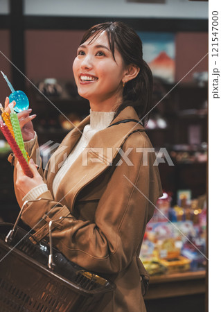 昔ながらの駄菓子屋で懐かしく買い物をする若い女性【撮影協力・お米・駄菓子屋 加賀田米穀店】 121547000