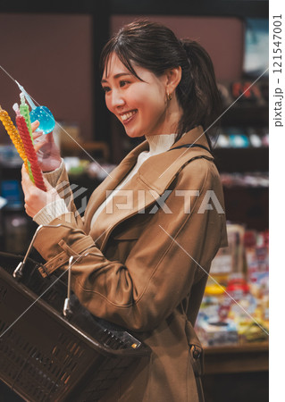 昔ながらの駄菓子屋で懐かしく買い物をする若い女性【撮影協力・お米・駄菓子屋 加賀田米穀店】 121547001