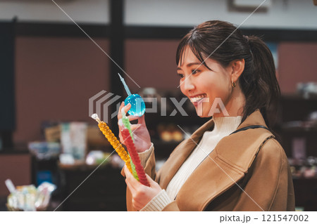 昔ながらの駄菓子屋で懐かしく買い物をする若い女性【撮影協力・お米・駄菓子屋 加賀田米穀店】 121547002