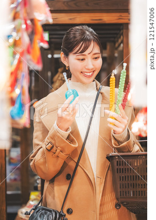 昔ながらの駄菓子屋で懐かしく買い物をする若い女性【撮影協力・お米・駄菓子屋 加賀田米穀店】 121547006