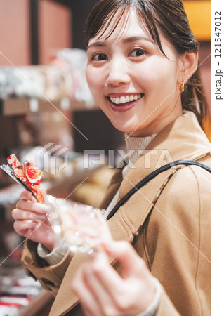 昔ながらの駄菓子屋で懐かしく買い物をする若い女性【撮影協力・お米・駄菓子屋 加賀田米穀店】 121547012