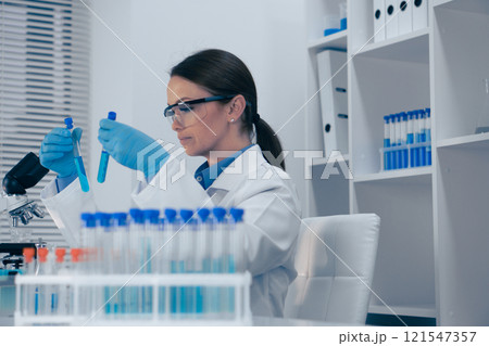 A scientist is performing a detailed analysis of various test tubes in a stateoftheart modern laboratory setting, contributing to advancements in biotechnology, chemistry, and healthcare A scientist is performing a detailed analysis of various test tubes in a stateoftheart modern laboratory setting, contributing to advancements in biotechnology, chemistry, and healthcare 121547357