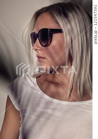 Stylish woman wearing sunglasses with soft shadow overlay on a neutral background Stylish woman wearing sunglasses with soft shadow overlay on a neutral background 121547391
