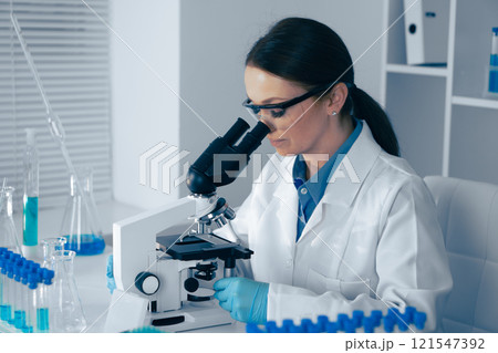In a modern lab, a skilled female scientist analyzes biological and chemical samples under a microscope, using advanced equipment for precise research vital to health and technology development In a modern lab, a skilled female scientist analyzes biological and chemical samples under a microscope, using advanced equipment for precise research vital to health and technology development 121547392