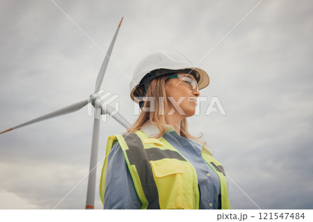 A Female Engineer stands confidently at a vast, sprawling wind farm, showcasing her strength and expertise in a maledominated field while symbolizing the future of sustainable energy and diversity A Female Engineer stands confidently at a vast, sprawling wind farm, showcasing her strength and expertise in a maledominated field while symbolizing the future of sustainable energy and diversity 121547484