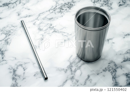 Modern mockup of a reusable straw next to a clean metal tumbler on a marble countertop 121550402