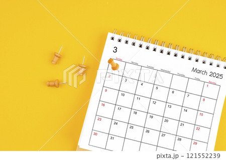 March 2025 Monthly desk calendar for 2025 year with wooden pin on yellow background. 121552239