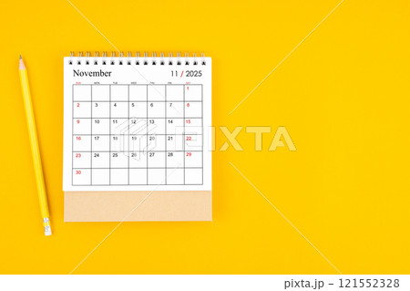 November 2025 desk calendar and wooden pencil on yellow color background. 121552328