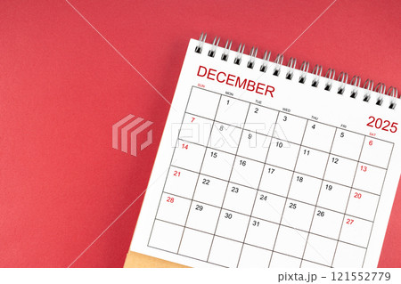 December 2025 desk calendar on red background. 121552779