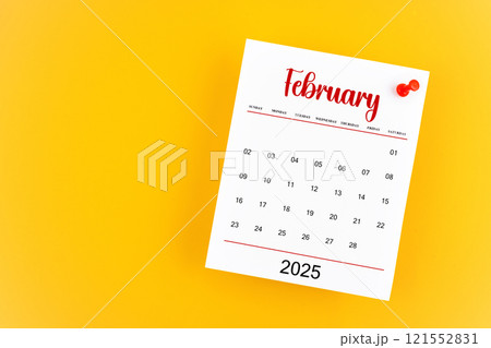 February 2025 calendar page with red push pin on yellow background. February 2025 calendar page with red push pin on yellow background. 121552831