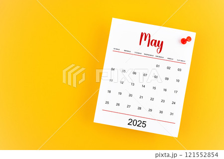 May 2025 calendar page with red push pin on yellow background. May 2025 calendar page with red push pin on yellow background. 121552854