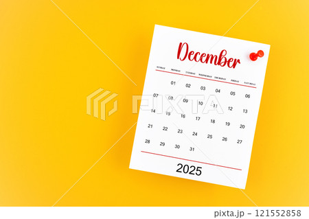 December 2025 calendar page with red push pin on yellow background. December 2025 calendar page with red push pin on yellow background. 121552858