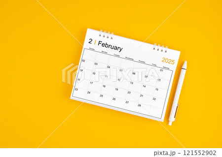 February 2025, Monthly desk calendar for 2025 year and pen on yellow background. 121552902