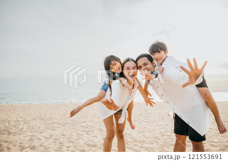 Vacation joy at the beach with a happy family. Parents and children laughing playing and enjoying the summer sun. Travel concept captured in this moment of relaxation and happiness Vacation joy at the beach with a happy family. Parents and children laughing playing and enjoying the summer sun. Travel concept captured in this moment of relaxation and happiness 121553691
