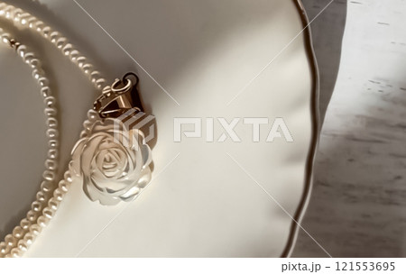 オフホワイトの皿にのった薔薇の彫り物のペンダントヘッドのついたネックレス 121553695