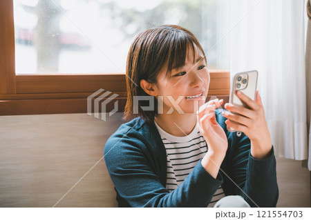 スマホを操作する笑顔の若い女性 スマホを操作する笑顔の若い女性 121554703