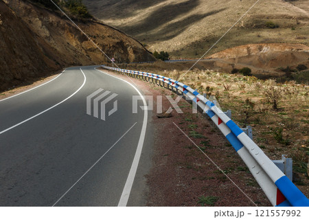 Curved highway winding through the mountainous terrain of Armenia under soft afternoon light Curved highway winding through the mountainous terrain of Armenia under soft afternoon light 121557992