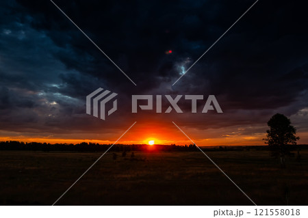 Picturesque sunset in a field after rain. Cloudy sundown sky Picturesque sunset in a field after rain. Cloudy sundown sky 121558018