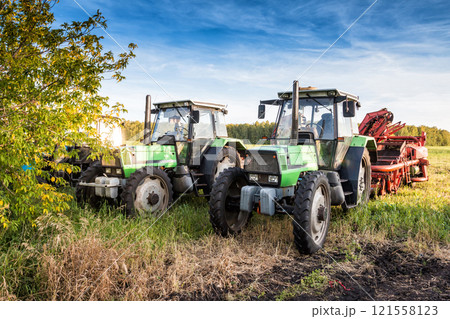Modern wheeled agricultural tractors with harvesting equipment on an field Modern wheeled agricultural tractors with harvesting equipment on an field 121558123
