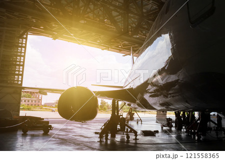 White passenger airliner under maintenance in the hangar. Repair of jet plane White passenger airliner under maintenance in the hangar. Repair of jet plane 121558365