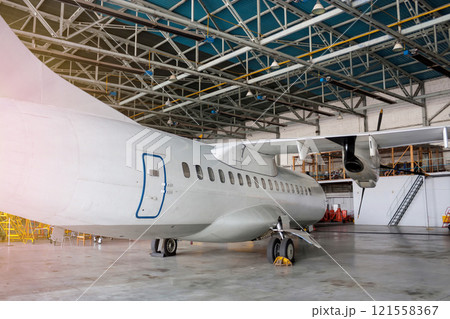 White passenger turboprop aircraft under maintenance in the hangar. Repair of airplane 121558367