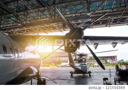 Passenger turboprop airplane and helicopter in the hangar. Rotorcraft and aircraft under maintenance 121558369