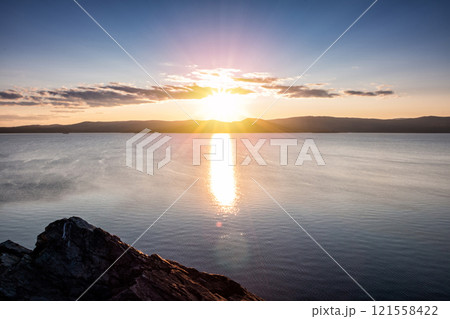 Beautiful lake and rocky shore in the rays of evening sun of golden autumn 121558422