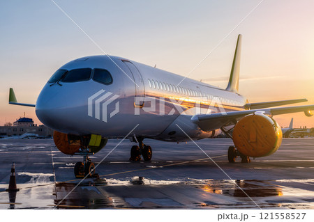Modern passenger airplane on the airport apron against the backdrop of a scenic sunset 121558527