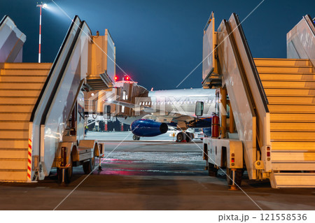 A view behind the mobile passenger ramps at the jet plane standing at the boarding bridge on the night airport apron 121558536