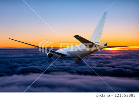 White wide body passenger airliner is flying in the sunset sky White wide body passenger airliner is flying in the sunset sky 121558693
