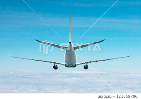 Rear view of a wide body passenger airplane flying in the air above the clouds Rear view of a wide body passenger airplane flying in the air above the clouds 121558706
