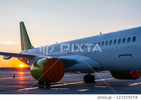 Close-up of the modern passenger airplane fuselage at sunset 121559259